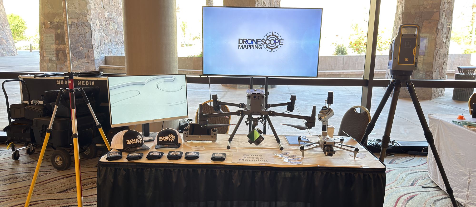 A Drone Scope Mapping equipment table — a multirotor aircraft, a laser scanner, GNSS tripods and screens showing captured data.